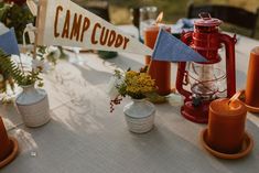 the table is set up with candles, vases and other items for an outdoor party