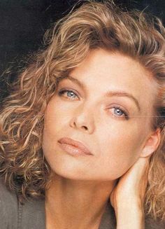 a woman with curly hair and blue eyes posing for a magazine cover photo in front of a black background