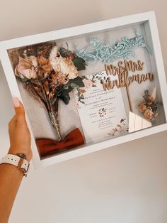 a person holding up a wedding card with flowers in the front and on the back