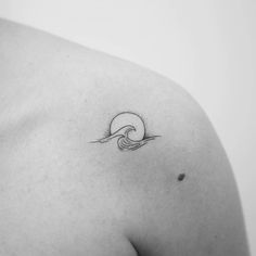 a black and white photo of a woman's shoulder with a wave tattoo on it