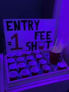 a table with cups and straws on it in front of a sign that says entry 1 fee shot