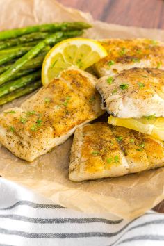 chicken breast with asparagus and lemon slices on parchment paper next to green beans