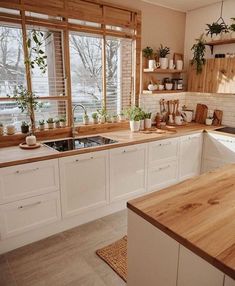 a kitchen filled with lots of wooden counter tops and white cabinets next to a window