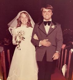 a man and woman standing next to each other in front of a church pews