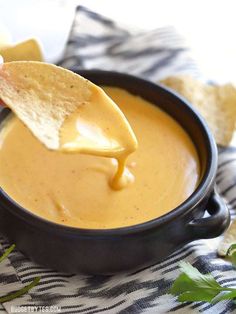 a tortilla chip being dipped with cheese sauce