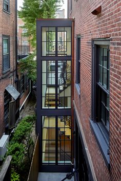 a narrow alleyway between two buildings with glass windows on each side and an open staircase leading up to the second floor