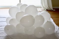 a bunch of white balloons sitting on top of a bed