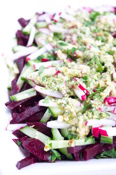 a salad with radishes, cucumbers and dressing on top is shown