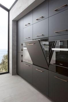 a modern kitchen with black cabinets and stainless steel appliances in front of a large window