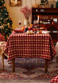 a dining room table covered with a red and white checkered tablecloth next to a christmas tree