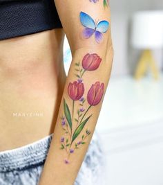 a woman's arm with flowers and butterfly tattoos on her left side ribcage