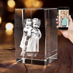 a person holding up a cell phone to take a photo of two children in a glass block