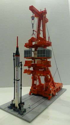 an orange and white rocket sitting on top of a table next to a black and white object