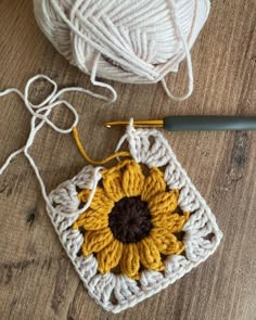 a crocheted sunflower sits next to a ball of yarn