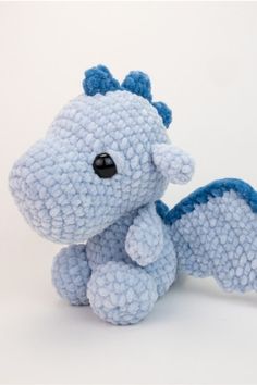 a blue stuffed dragon sitting on top of a white table