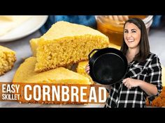 a woman holding a pan filled with cornbread next to other breads and butter