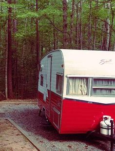 a red and white trailer parked in the woods