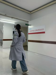 a woman in a long coat is walking through an empty building with her back to the camera