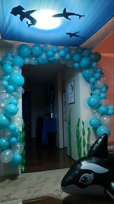 a room decorated with blue and white balloons in the shape of shark's heads