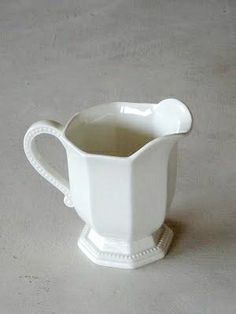 a white ceramic pitcher sitting on top of a table