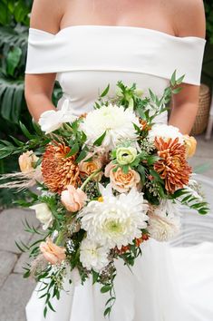 a bride holding a bouquet of white and orange flowers