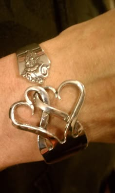 a silver bracelet with two heart shaped links on it's wrist and the words upper strut general store