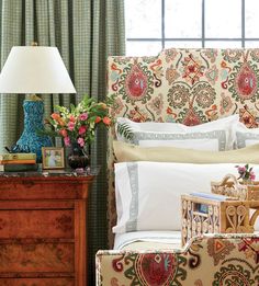 a bedroom with an ornate headboard and colorful pillows on it's side table