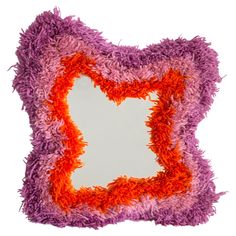 an orange and purple pillow with fringes on it's sides, in the shape of a heart