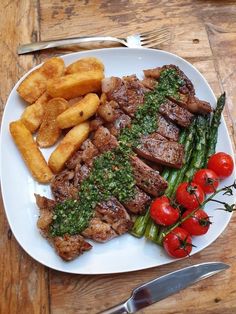 a white plate topped with meat and veggies on top of a wooden table