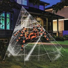 a spider web in front of a house with halloween decorations on the yard and lawn