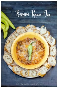 a yellow plate topped with food next to green peppers and bread on top of a wooden table