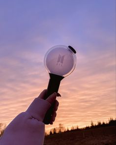 a hand holding a hair dryer in front of the sky at sunset or dawn