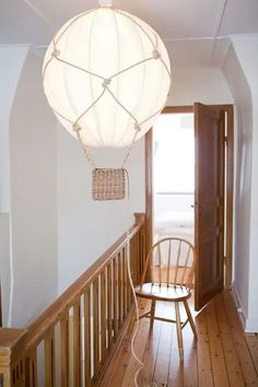 a light fixture hanging from the ceiling in a hallway next to a chair and door