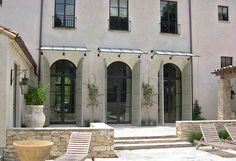 two lawn chairs sitting in front of a building with windows on each side and stone steps leading up to it