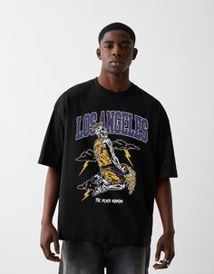 a man standing in front of a white wall wearing a black los angeles lakers t - shirt