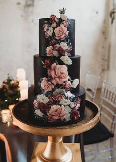 a three tiered black wedding cake decorated with flowers