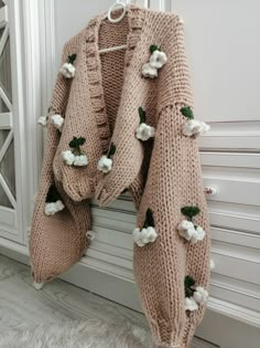 a knitted sweater with flowers hanging on a doorknott in front of a white radiator