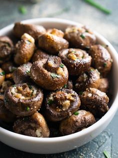 a white bowl filled with cooked mushrooms on top of a table