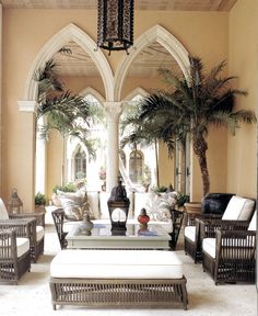 a living room filled with lots of furniture and palm trees in front of an archway