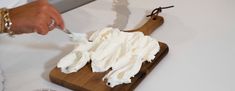 a person is spreading whipped cream on a cutting board