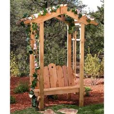 a wooden bench sitting in the middle of a yard with greenery growing on it