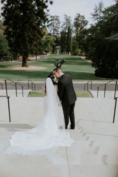 a bride and groom kissing on the steps at their wedding ceremony in front of an empty park