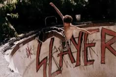 a man riding a skateboard up the side of a cement wall covered in graffiti