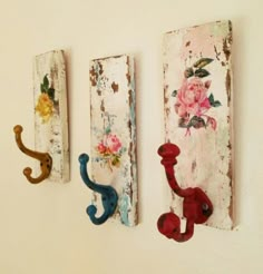 three wall hooks with flowers painted on them are hanging on the wall next to each other