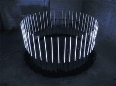 an artistic sculpture made out of sticks in the shape of a circle with lights on it