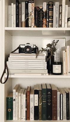 the books are stacked on top of each other in front of a white bookcase