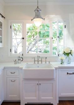 a white kitchen with two windows and a sink