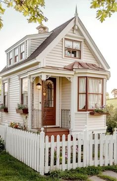 a small white house with a picket fence around it's front door and windows