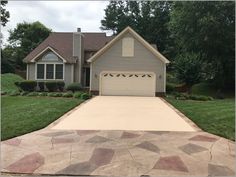 a house with a driveway in front of it and grass on the lawn behind it