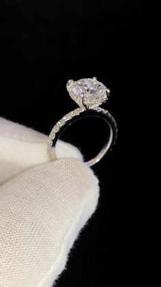 an engagement ring is shown on top of a white cloth in front of a black background